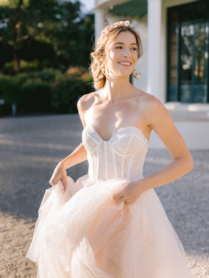 Bride running with a happy smile, wearing a flow wedding dress with matching bridal gold and blush accessories