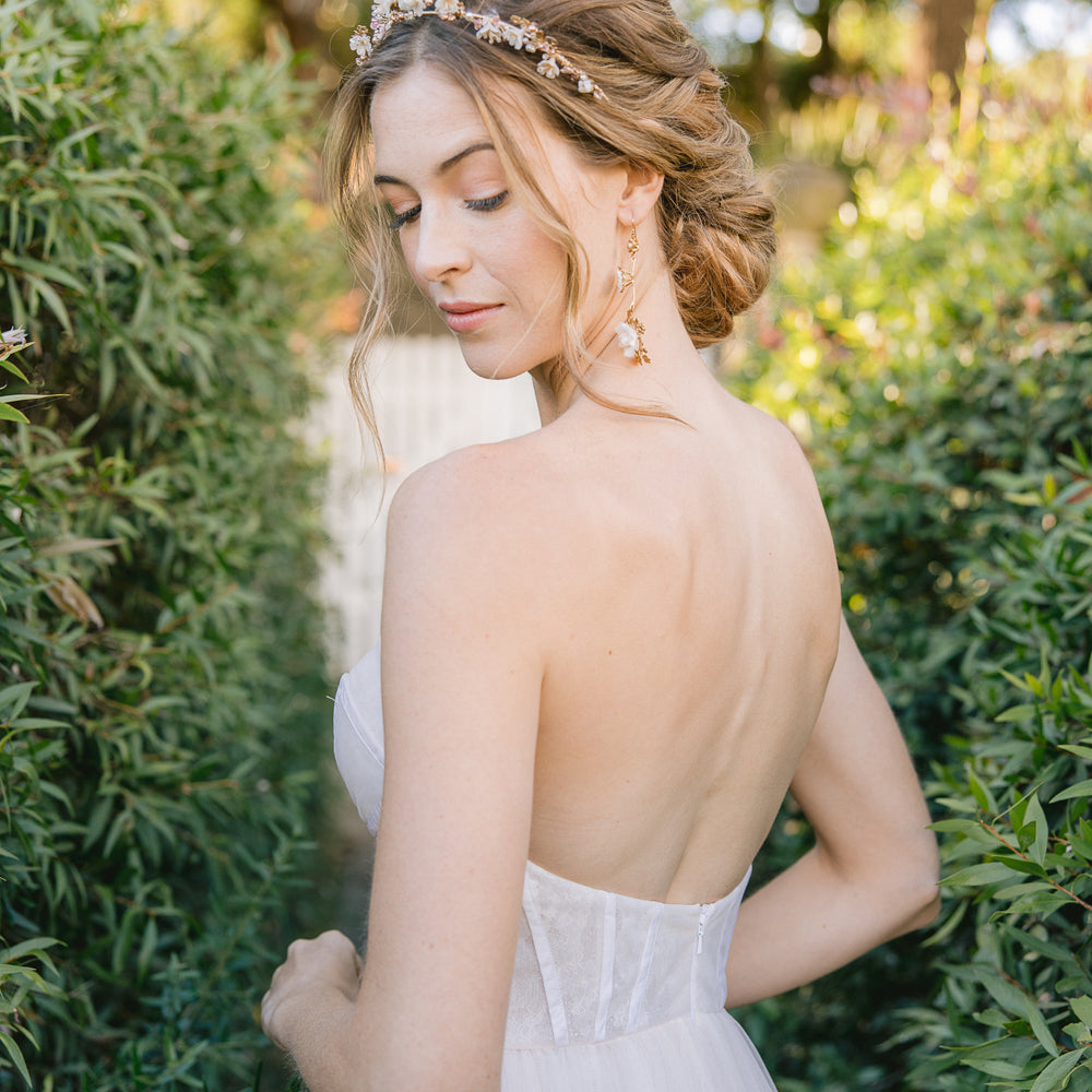 bride wearing a floral wedding crown with blush pearls with an updo and floral gold drop earrings