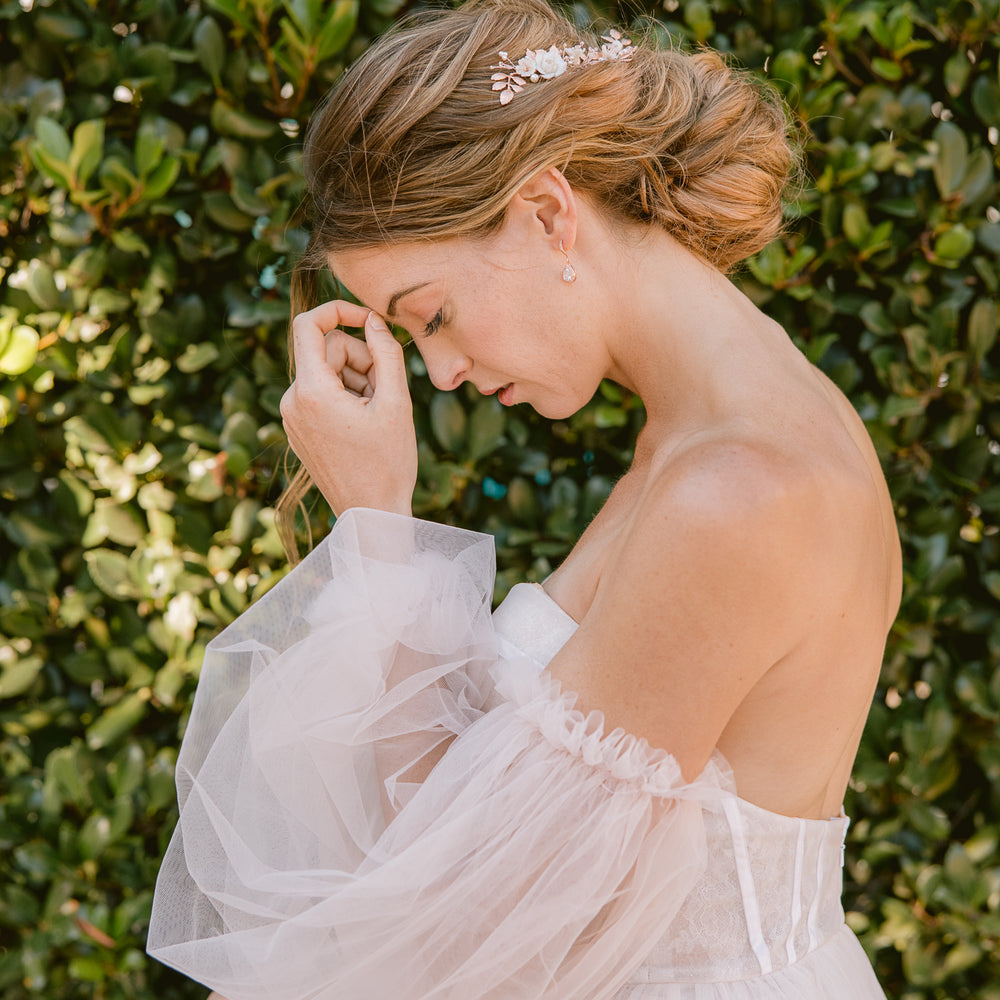 Bride wearing a puffy sleeved blush tulle gown and rose gold hair accessories and jewellery with crystals and pearls