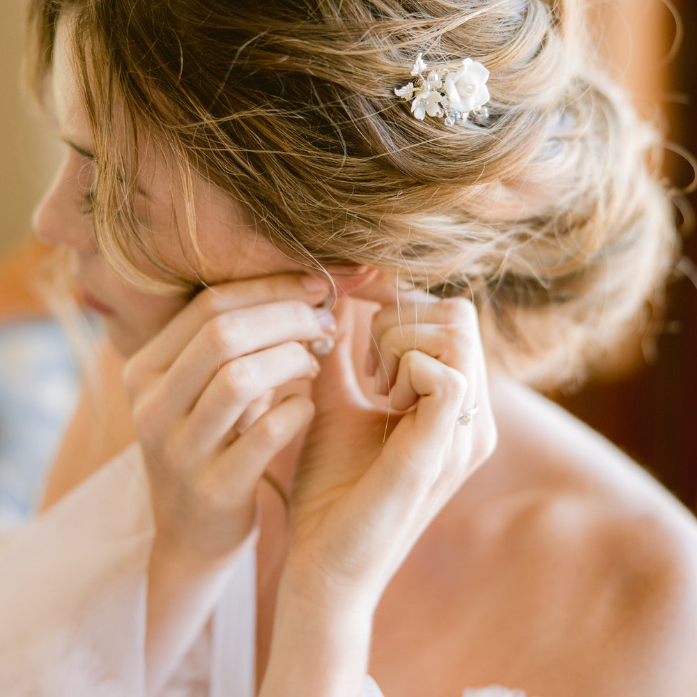 Bride putting on earrings and wedding hair comb when getting ready