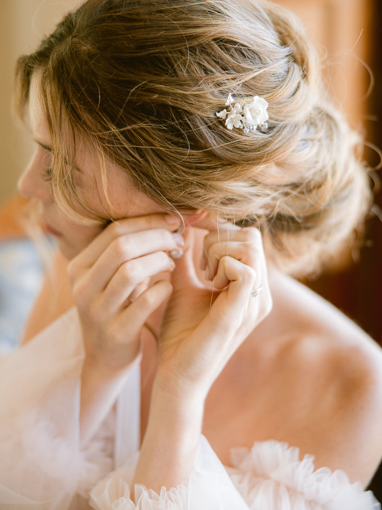 Bride putting on earrings and wedding hair comb when getting ready