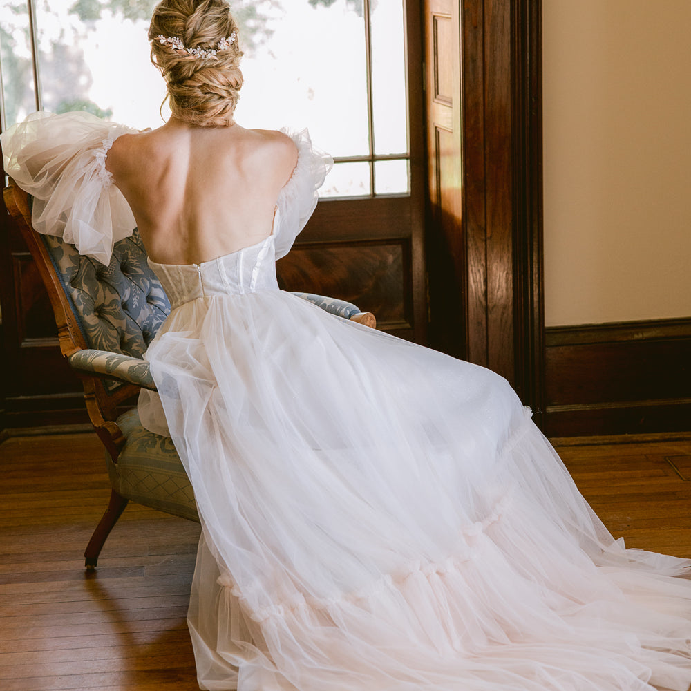 Rose gold bridal hair piece for updo or hair down on bride with tulle wedding gown sitting in a vintage armchair