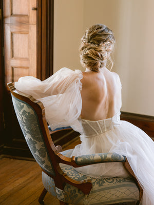 Rose gold bridal hair piece for updo or hair down on bride with tulle wedding gown sitting in a vintage armchair